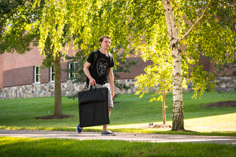 student walking with an art portfolio